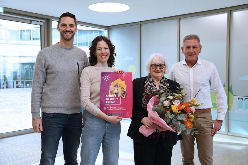 Die Betriebsratsvorsitzenden Markus Fichtl und Thomas Kleinert überreichen im Foyer des Verwaltungsgebäudes von REWAG und das.Stadtwerk.Regensburg einen Spendencheck und Blumen an Karin Roth und Margit Kunc vom Verein Frauen helfen Frauen e.V. – die offizielle Spendenübergabe für das Projekt.