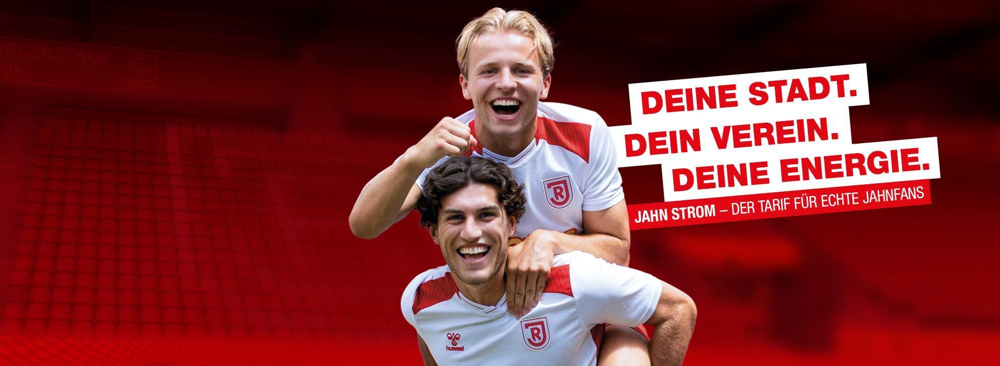 Zwei Fußballspieler des SSV Jahn Regensburg in weißen Trikots mit roten Akzenten und dem "Netto"-Logo posieren lachend vor rotem Hintergrund. Daneben steht der Slogan: "Deine Stadt. Dein Verein. Deine Energie"