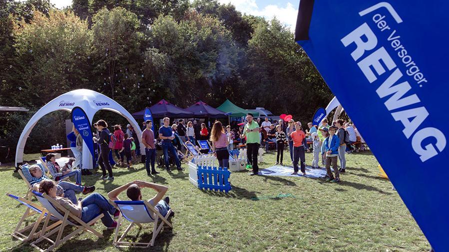 Gäste entspannen in Liegestühlen und informieren sich an Infoständen beim REWAG-Event Tag der offenen Tür