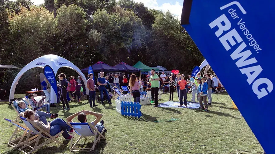 Gäste entspannen in Liegestühlen und informieren sich an Infoständen beim REWAG-Event Tag der offenen Tür
