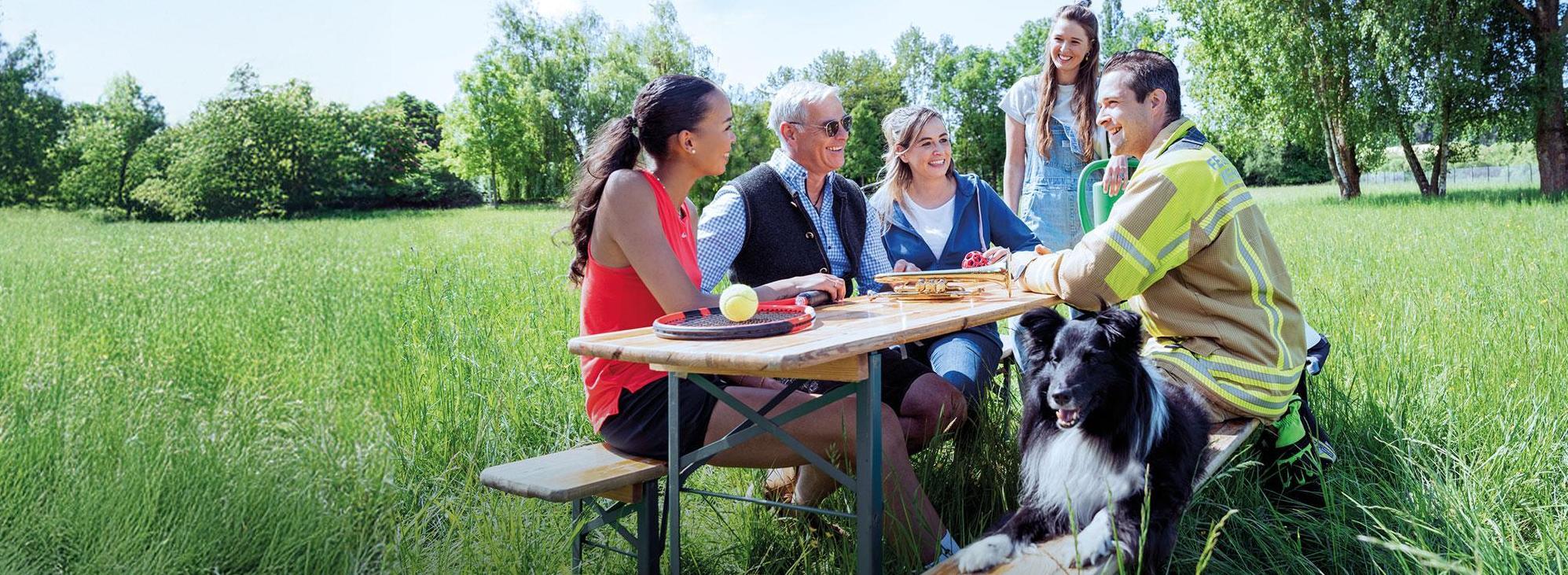 Eine Gruppe fröhlicher Vereinsmitglieder zusammen an einem Tisch im Freien
